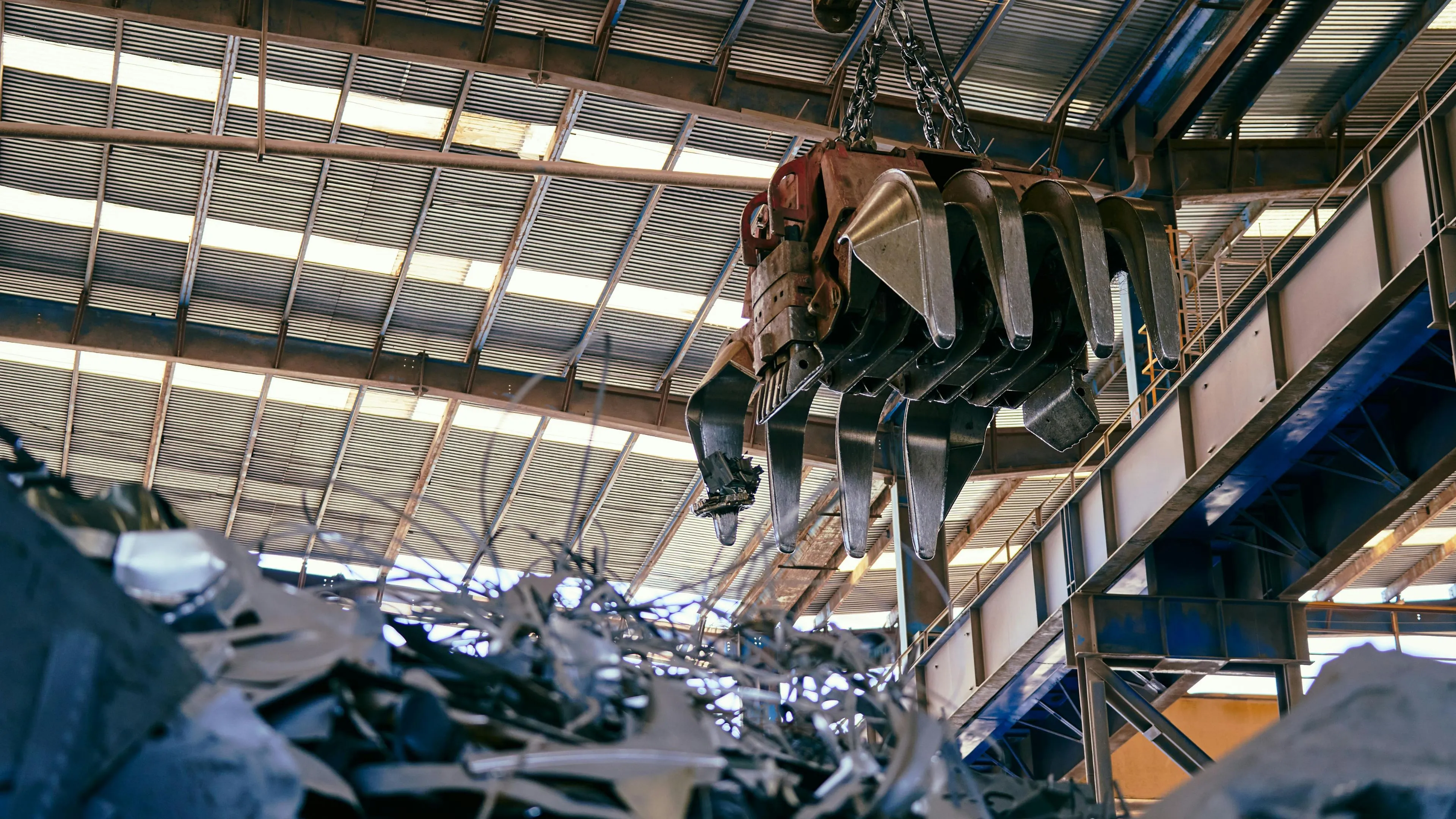 An overhead scrap-handling grapple sorting metal at a recycling facility